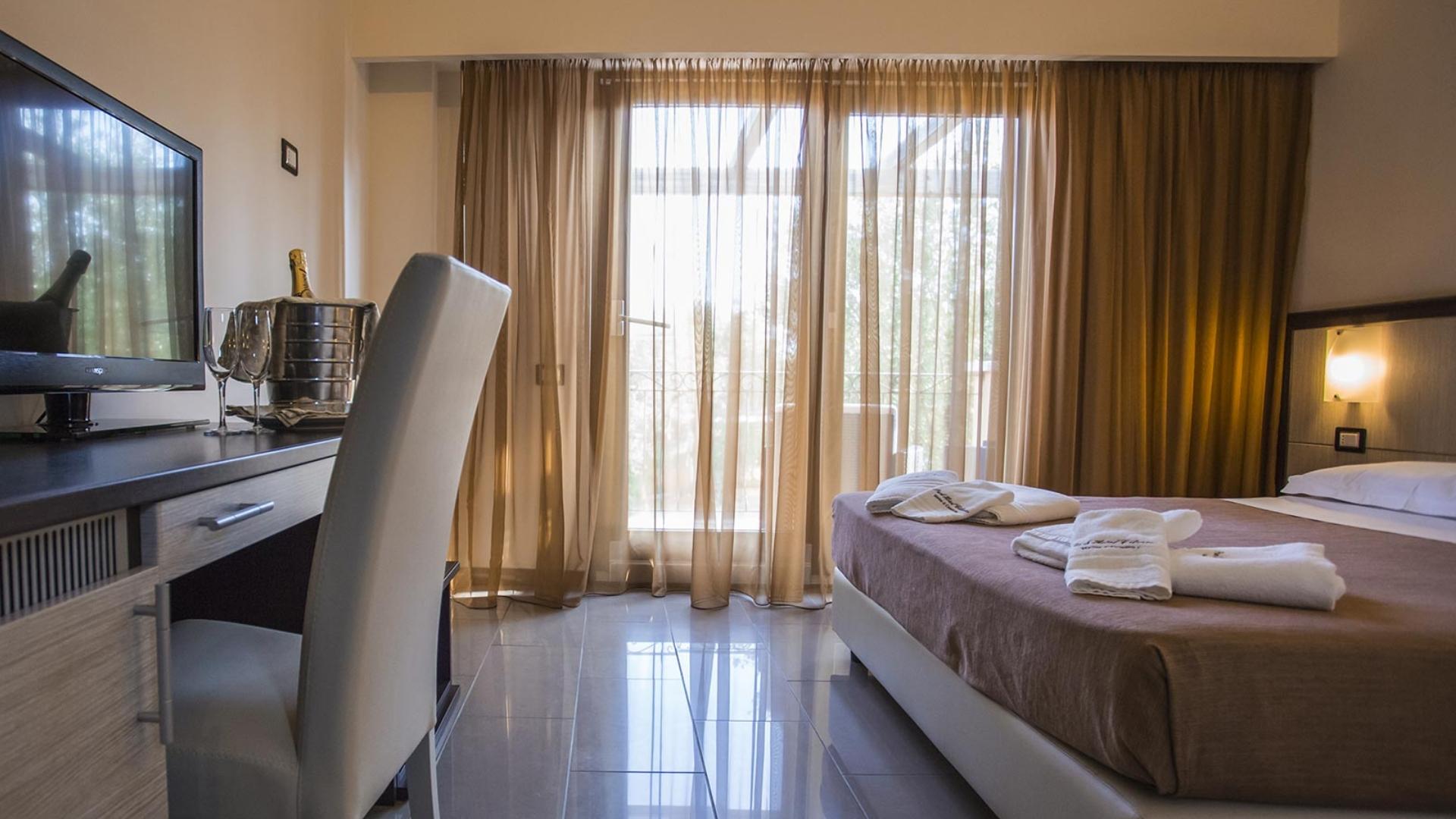 Camera d'hotel accogliente con letto matrimoniale, TV e bottiglia di champagne.