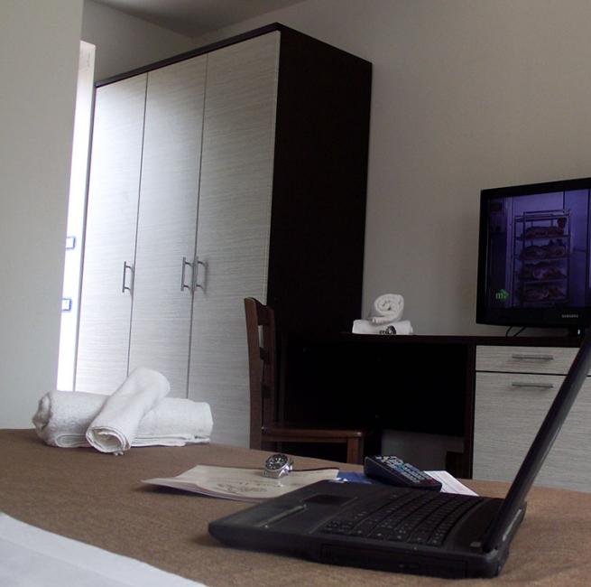 Camera d'albergo con laptop, TV, armadio e asciugamani.