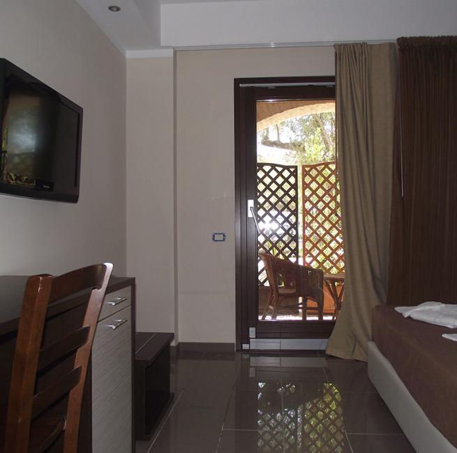 Camera d'albergo moderna con TV, scrivania e balcone con sedie.