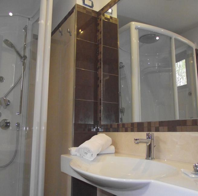 Bagno moderno con doccia idromassaggio, lavabo e specchio.