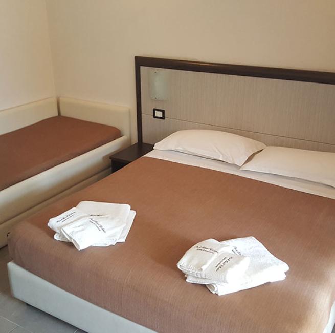 Camera con letto matrimoniale e divano, asciugamani piegati sul letto.