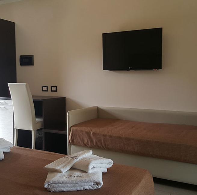 Camera d'albergo moderna con letto, TV a parete e scrivania.