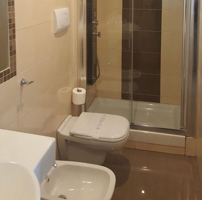 Bagno moderno con doccia in vetro, bidet e sanitari bianchi.