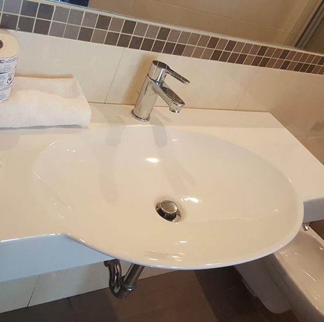 Bagno moderno con lavandino, asciugamani, prodotti da toeletta e servizi igienici.